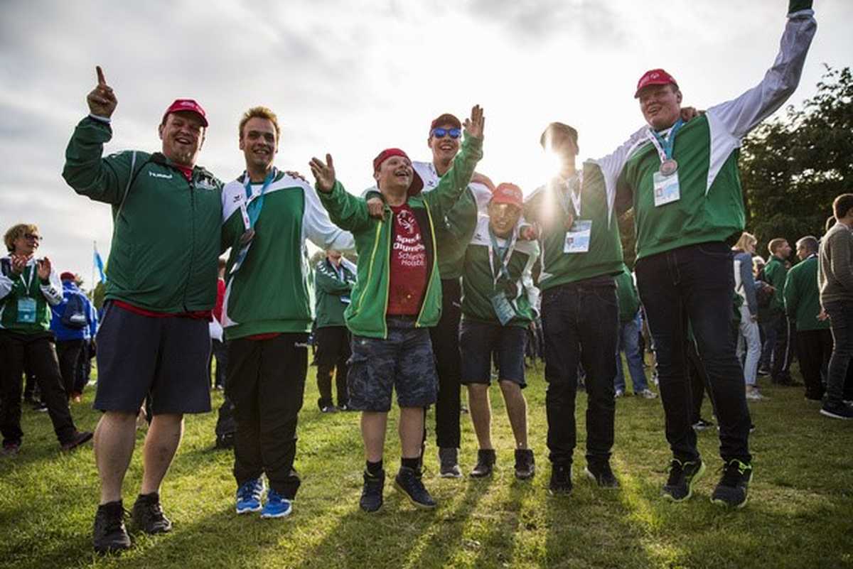 Sieben männliche Teilnehmer in  grünen Special Olympics Trikots freuen sich über den Sieg nach einer Teilnahme am Wettbewerb