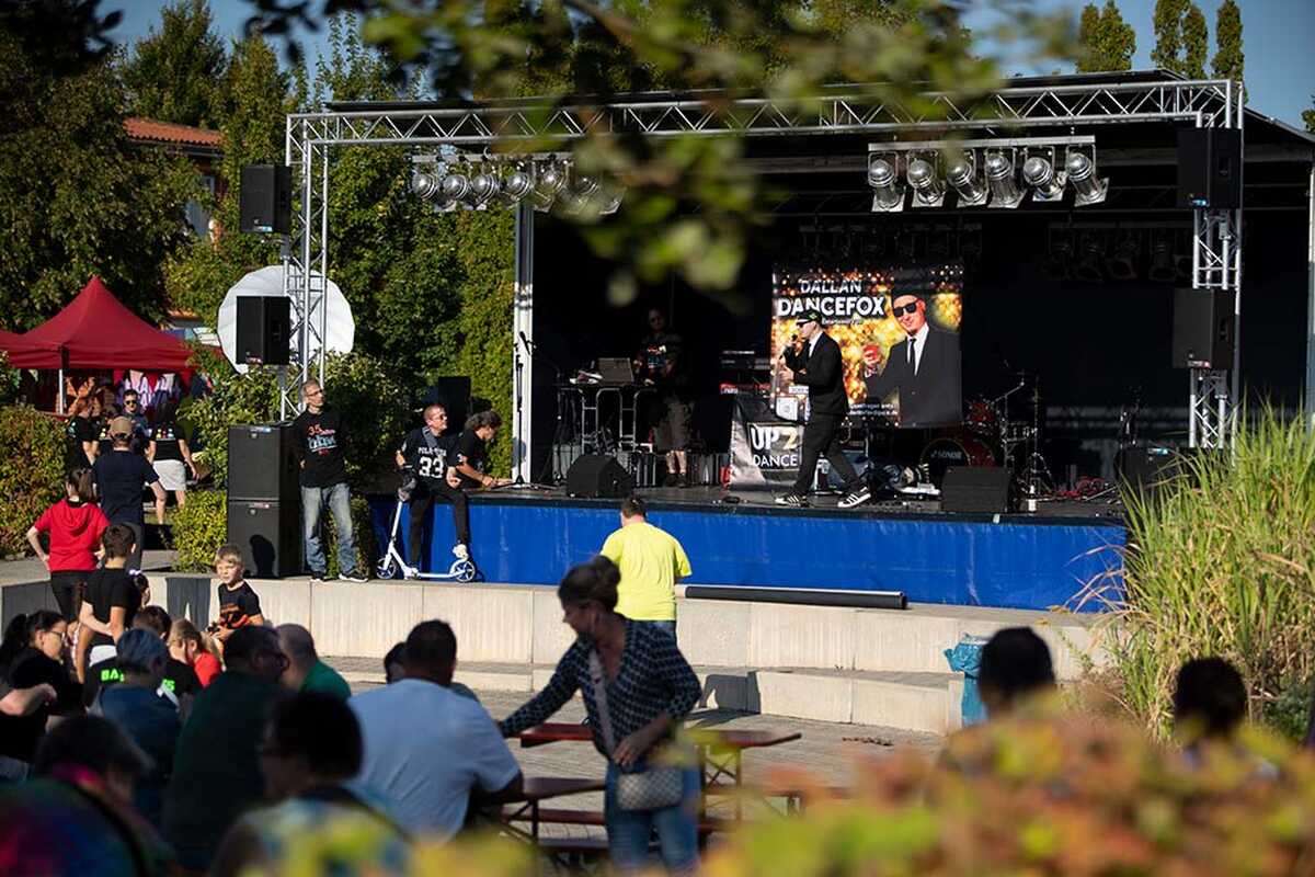 Werbebild für den Tag der offenen Tür der Halleschen Behindertenwerkstätten e. V. am 5. September 2026 in Halle (Saale). Eine Open-Air-Bühne mit Liveprogramm und zahlreiche Besucherinnen und Besucher vermitteln die Atmosphäre der Veranstaltung.
