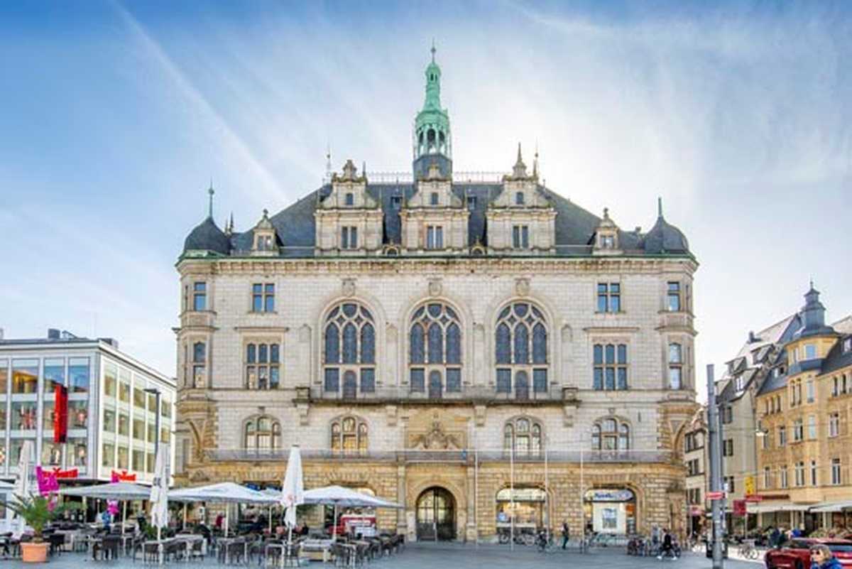 Ansicht Stadthaus von Norden aus, markant sind die drei großen Bogenfenster des Festsaales mit davorliegendem Balkon, mittlerer Turmspitze sowie den Erkern rechts und links, die als Türme angesetzt sind. Das gebäude selbst ist mit gelbem Sandstein errichtet.