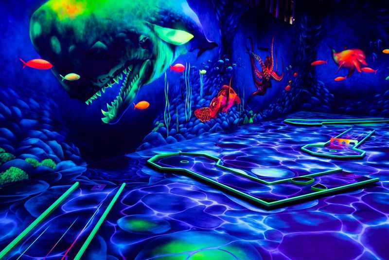 Blick in einen in Schwarzlicht gehüllten Minigolf-Raum in den BWG 5 Welten